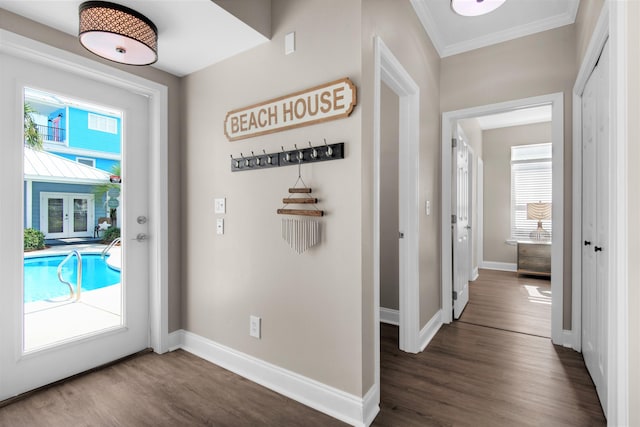 entryway with dark wood-style floors, crown molding, and baseboards