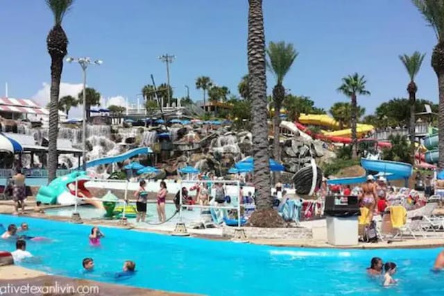 community pool featuring a water slide and a water play area