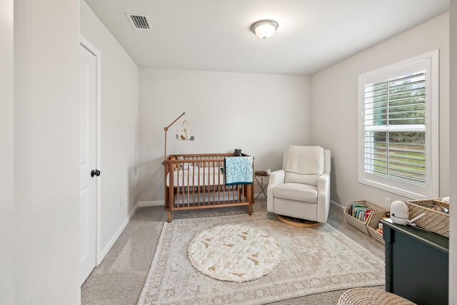 carpeted bedroom featuring a nursery area