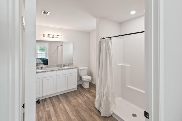 bathroom with toilet, hardwood / wood-style floors, vanity, and curtained shower