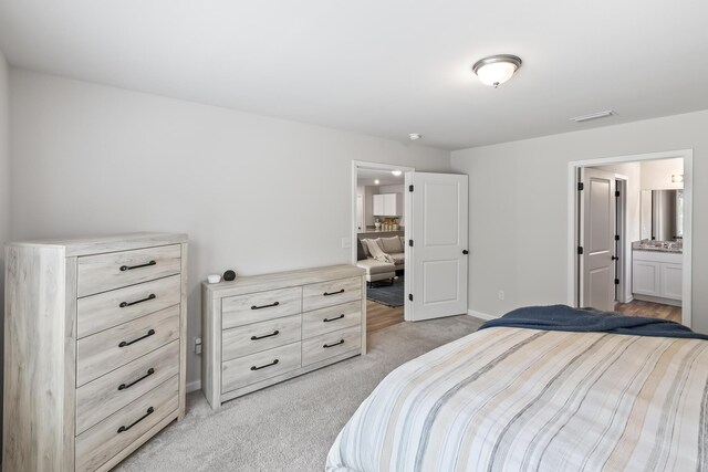 bedroom featuring light colored carpet and ensuite bathroom