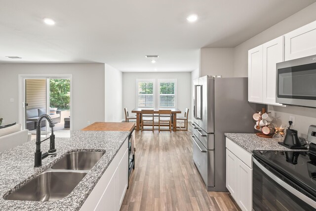 kitchen featuring sink, light hardwood / wood-style flooring, light stone countertops, electric stove, and white cabinetry