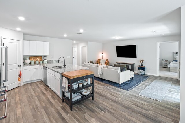 kitchen featuring sink, wood-type flooring, dishwasher, kitchen peninsula, and white cabinets