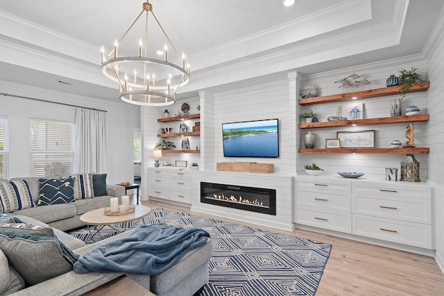 living room featuring crown molding, light hardwood / wood-style flooring, a tray ceiling, and a chandelier