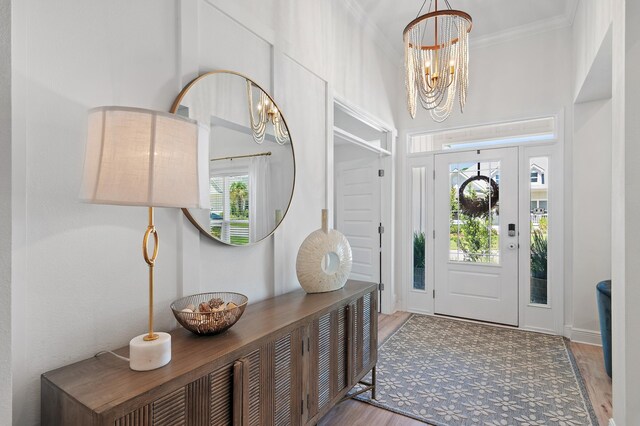 entryway featuring hardwood / wood-style flooring, an inviting chandelier, crown molding, and a healthy amount of sunlight