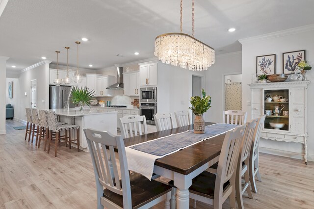 dining space with light wood-type flooring, crown molding, and a chandelier