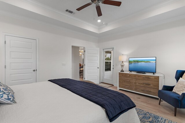 bedroom with ornamental molding, light wood-type flooring, a tray ceiling, ceiling fan, and ensuite bathroom