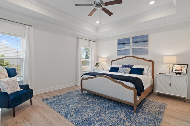 bedroom with a tray ceiling, light hardwood / wood-style flooring, ceiling fan, and ornamental molding