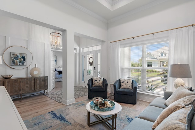 living room with an inviting chandelier, light hardwood / wood-style flooring, and crown molding