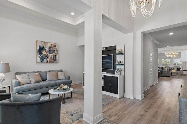 living room with hardwood / wood-style flooring, a high ceiling, a notable chandelier, and ornamental molding