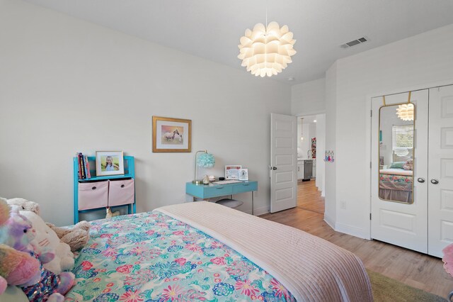 bedroom with a closet, light hardwood / wood-style floors, and a chandelier