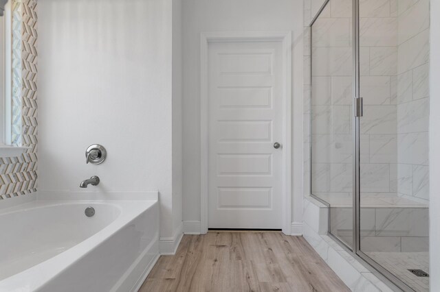 bathroom with independent shower and bath and hardwood / wood-style floors