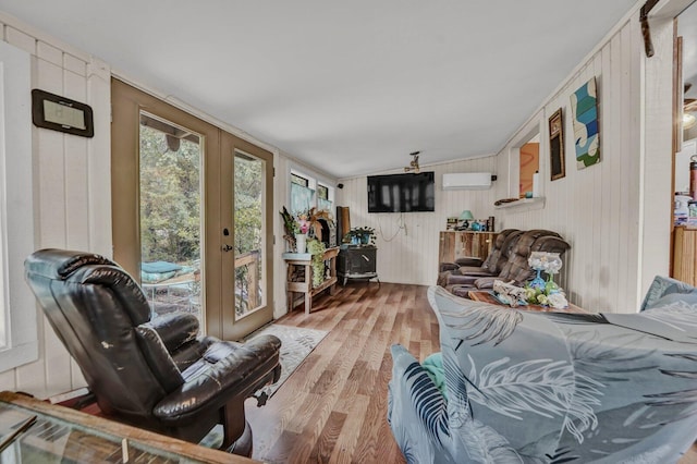 living room featuring a wall mounted AC, french doors, and light wood-type flooring