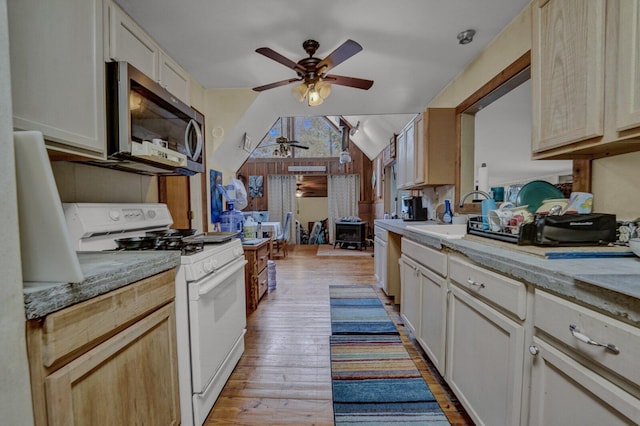 kitchen featuring ceiling fan, vaulted ceiling, light hardwood / wood-style floors, sink, and white range oven