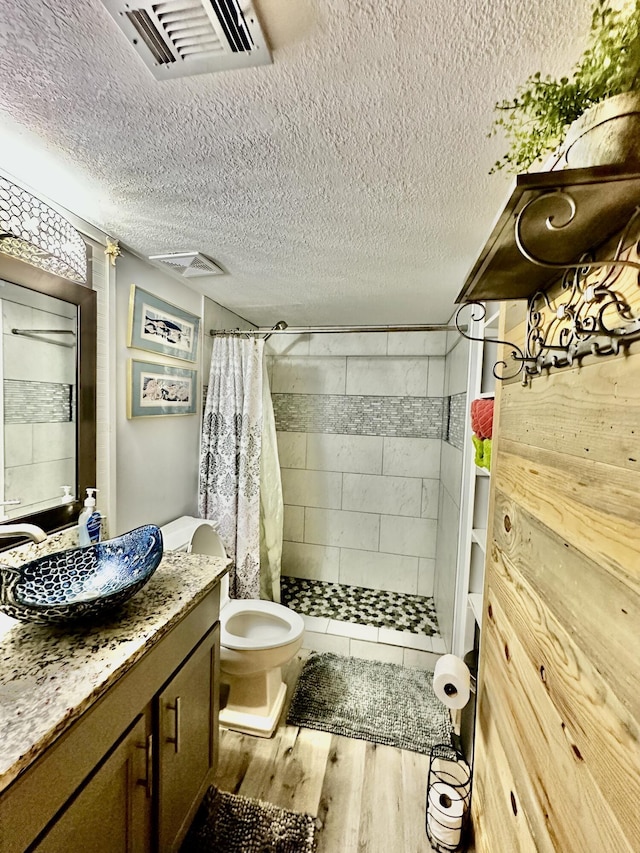 full bath with visible vents, wood finished floors, a textured ceiling, vanity, and a shower stall