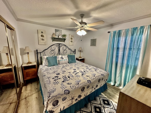 bedroom with ornamental molding, ceiling fan, light wood-style flooring, and a textured ceiling