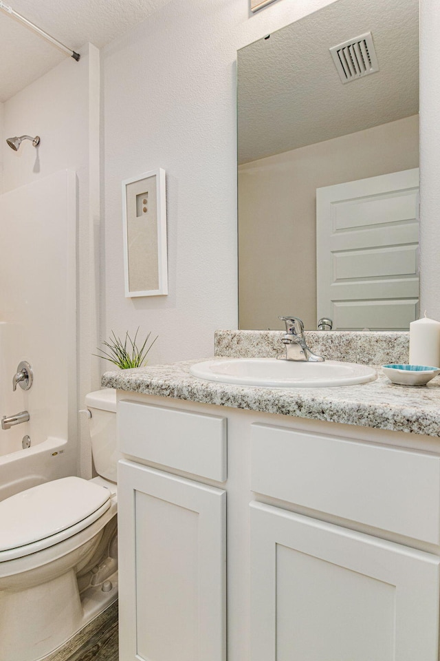 full bathroom with tub / shower combination, hardwood / wood-style floors, a textured ceiling, toilet, and vanity