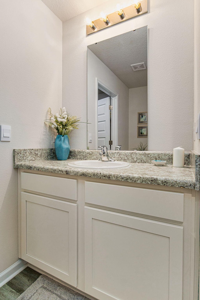 bathroom featuring vanity, wood-type flooring, and a textured ceiling