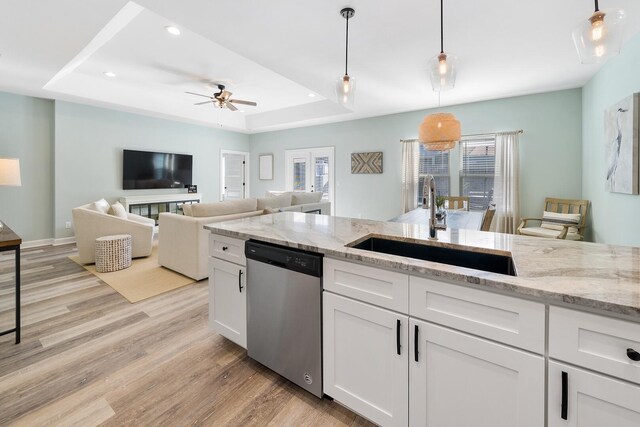 kitchen featuring light hardwood / wood-style flooring, stainless steel dishwasher, a tray ceiling, ceiling fan, and white cabinets