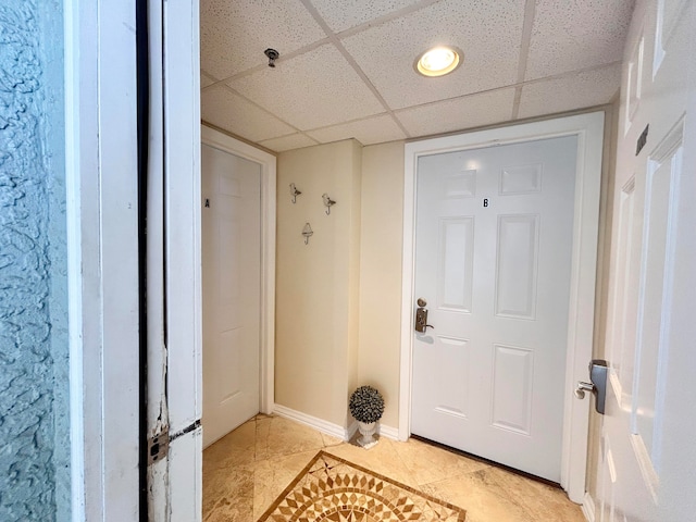 doorway to outside with a drop ceiling and light tile patterned floors