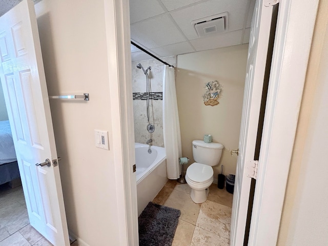 bathroom featuring shower / bathtub combination with curtain, toilet, and a drop ceiling