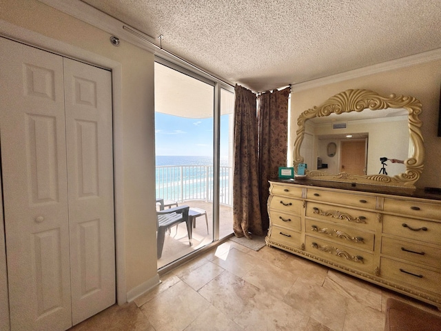 unfurnished bedroom featuring access to exterior, expansive windows, a textured ceiling, a closet, and a water view