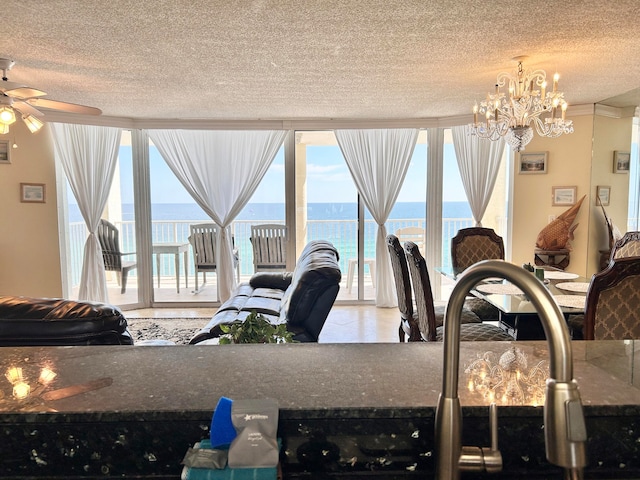 interior space featuring ceiling fan with notable chandelier, a water view, and a textured ceiling