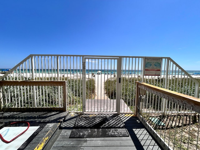 wooden terrace featuring a water view and a beach view