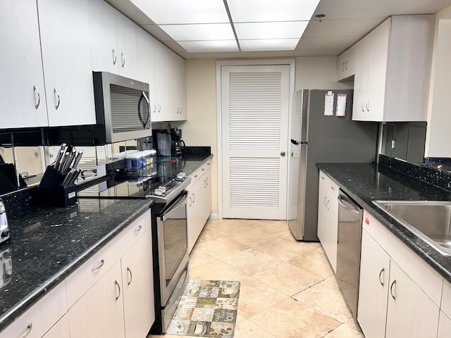 kitchen with white cabinets, stainless steel appliances, and dark stone counters