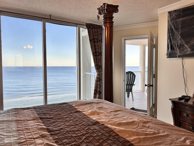 unfurnished bedroom featuring a water view, ornamental molding, a textured ceiling, and multiple windows