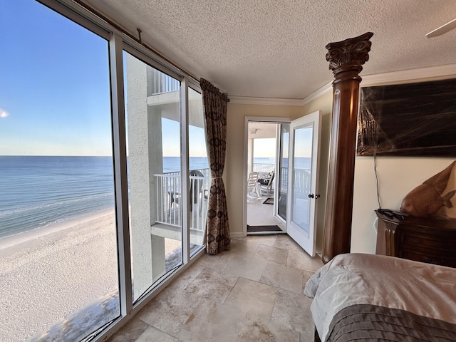 unfurnished bedroom featuring access to exterior, a beach view, a textured ceiling, a water view, and ornamental molding