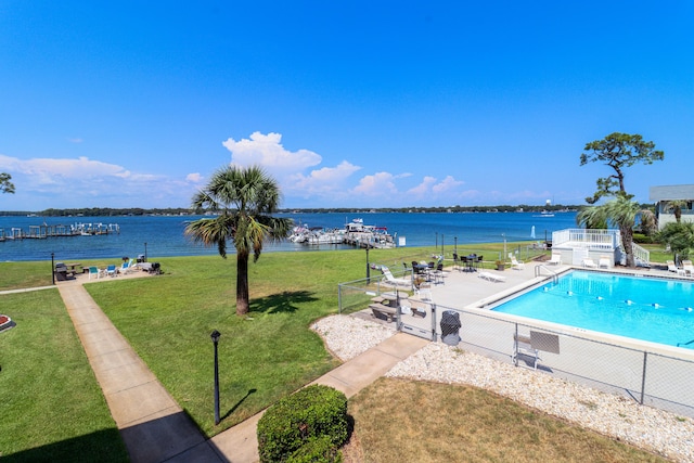 view of swimming pool featuring a water view and a lawn