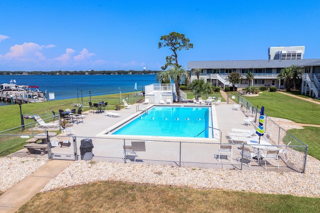 view of pool featuring a water view, a patio area, and a yard