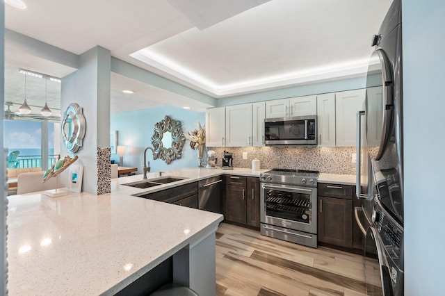 kitchen featuring sink, decorative backsplash, light hardwood / wood-style floors, white cabinetry, and stainless steel appliances