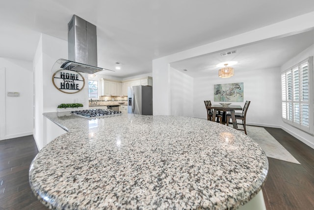 kitchen with island range hood, visible vents, appliances with stainless steel finishes, light stone countertops, and dark wood-style floors