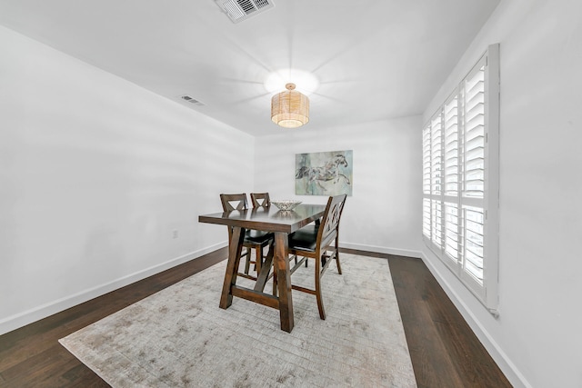 dining area featuring dark wood-style flooring, visible vents, and baseboards