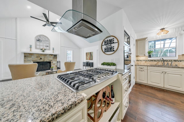 kitchen featuring dark wood finished floors, lofted ceiling, appliances with stainless steel finishes, light stone counters, and island exhaust hood