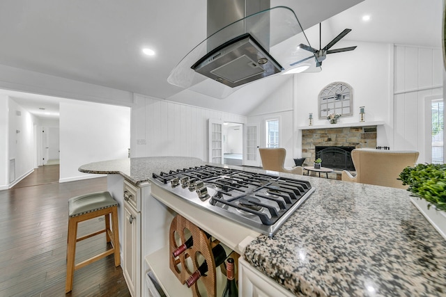 kitchen featuring dark stone counters, a breakfast bar area, white cabinetry, and stainless steel gas stovetop