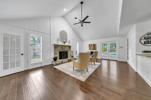 unfurnished living room with dark wood-type flooring, french doors, ceiling fan, and a stone fireplace