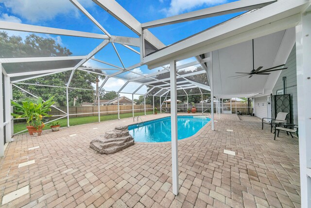 view of swimming pool with ceiling fan, a patio, and a lanai