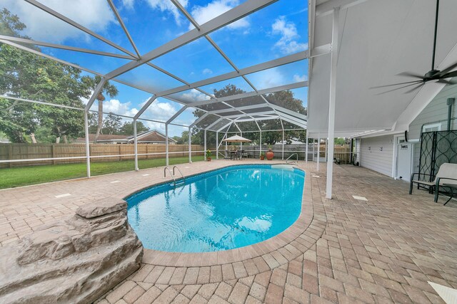 view of swimming pool featuring glass enclosure, a patio, ceiling fan, and a lawn