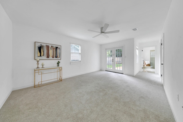 unfurnished living room with light colored carpet, visible vents, baseboards, a ceiling fan, and french doors