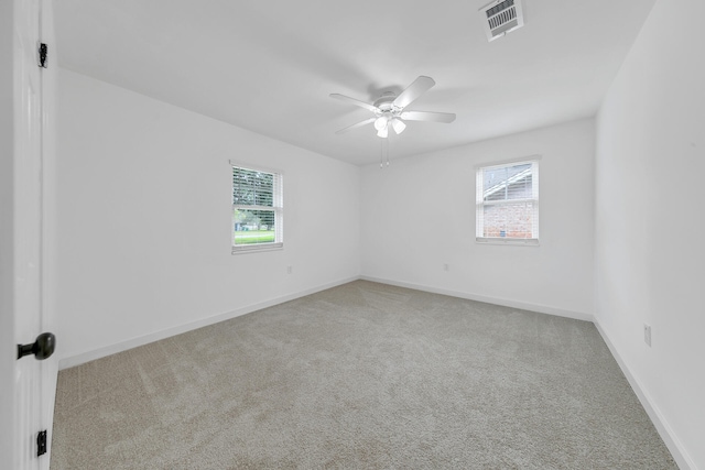 empty room with plenty of natural light, ceiling fan, and carpet