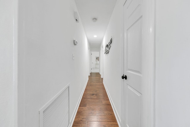 hall with dark wood-style flooring, visible vents, and baseboards