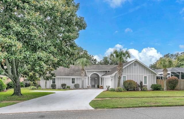 ranch-style home with board and batten siding, a front yard, fence, a garage, and driveway