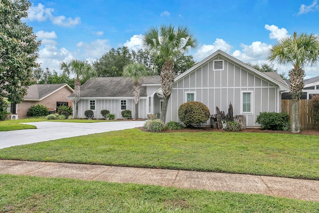 view of front of property with driveway, fence, board and batten siding, and a front yard