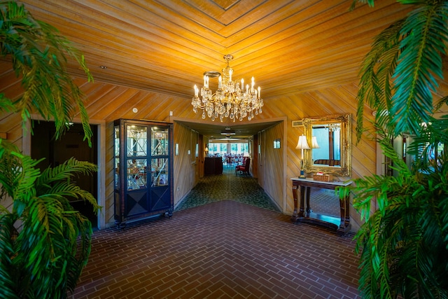 interior space with brick floor, a notable chandelier, and wood walls