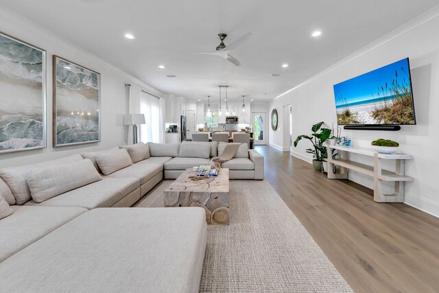 living room featuring light hardwood / wood-style flooring, ceiling fan, and ornamental molding