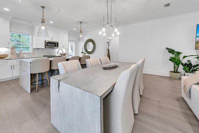 dining room featuring crown molding and light hardwood / wood-style flooring