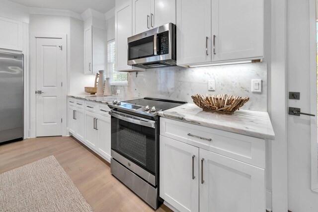 kitchen with appliances with stainless steel finishes, light hardwood / wood-style flooring, light stone counters, tasteful backsplash, and white cabinetry